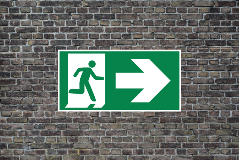 Grünes Exit Zeichen auf einer Mauer 