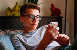 Video Clips für die Finanzbildung Jugendlicher Junge sitzt am Smartphone und schaut Videos