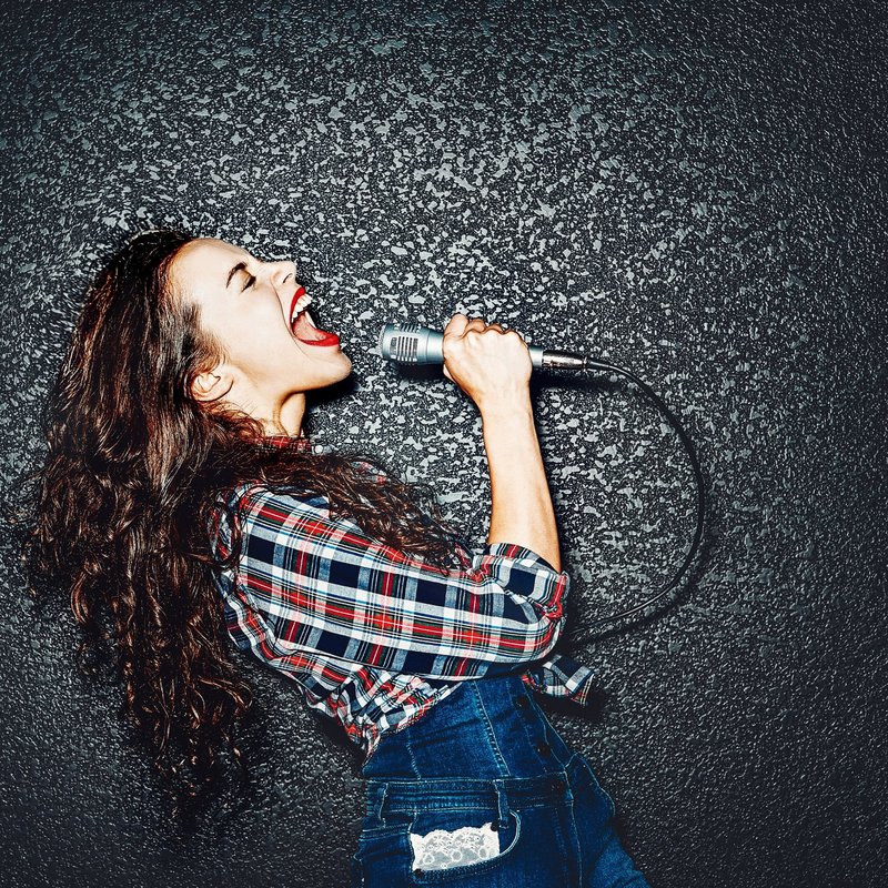 Frau die in ein Mikrofon singt. 