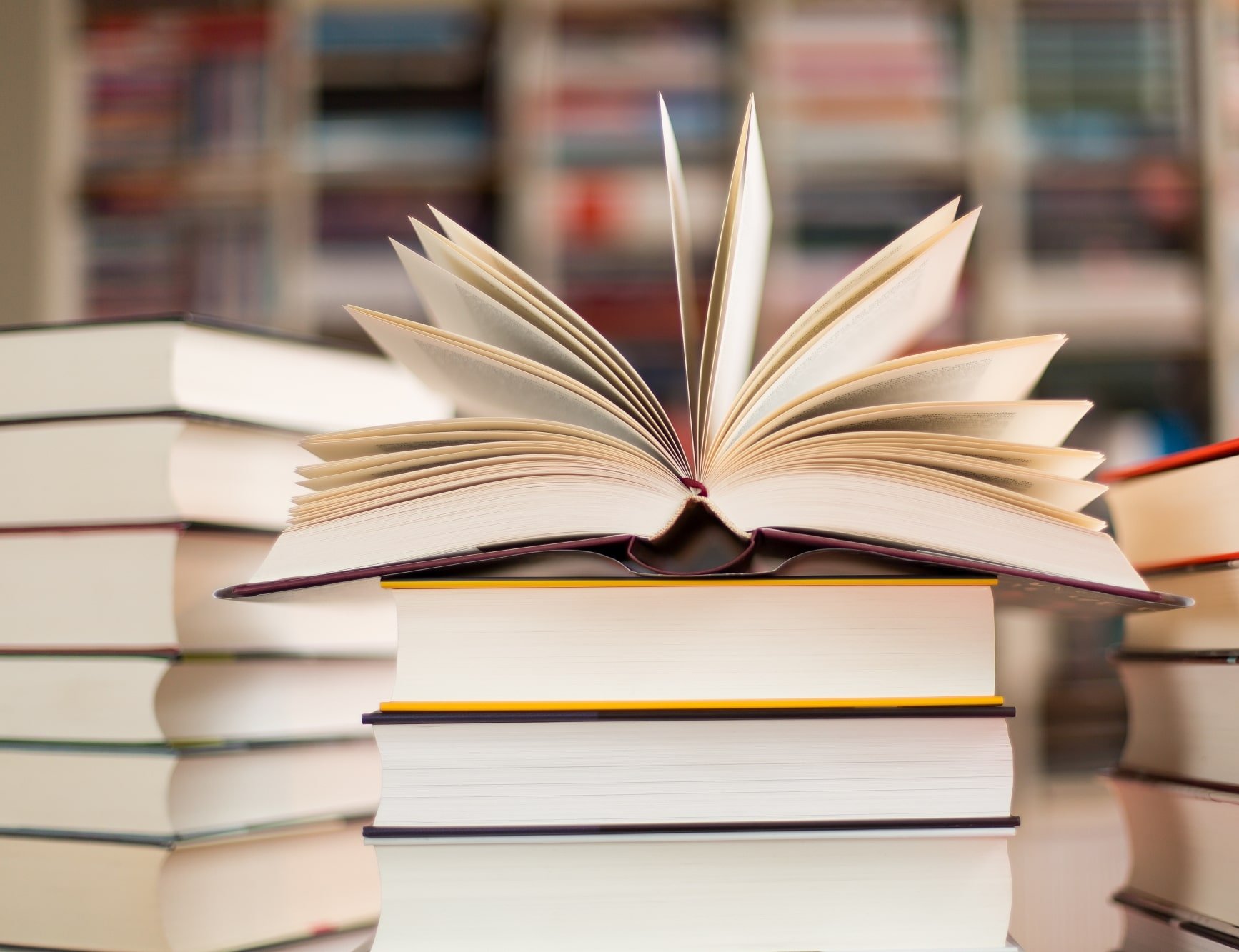 Ein Bücherstapel wobei das oberste Buch aufgeschlagen ist