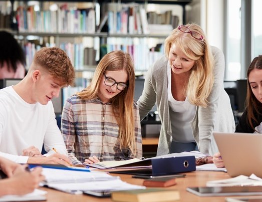 Lehrkraft steht bei Lernenden