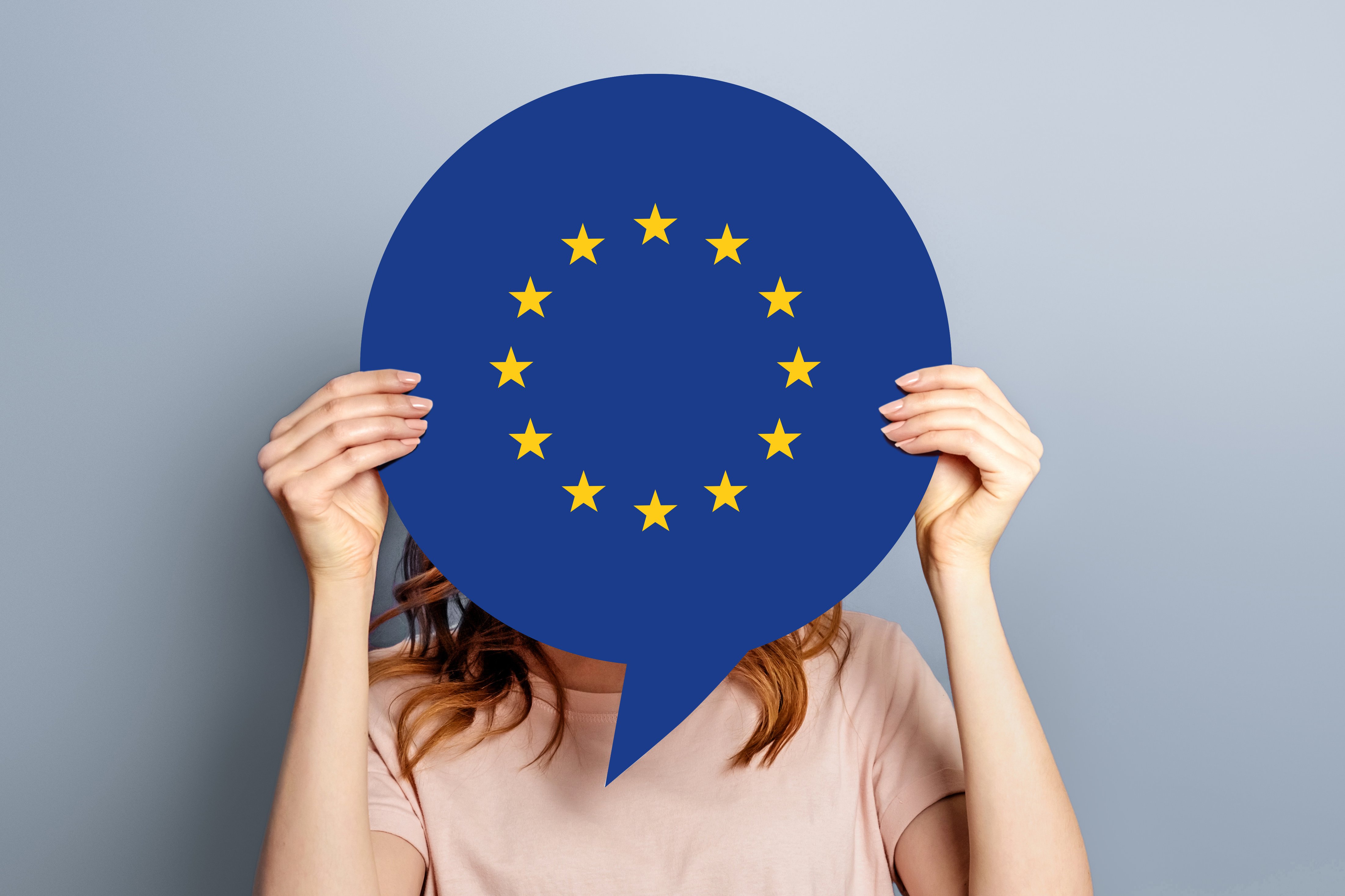 Frau hält Europaflagge vor ihrem Gesicht