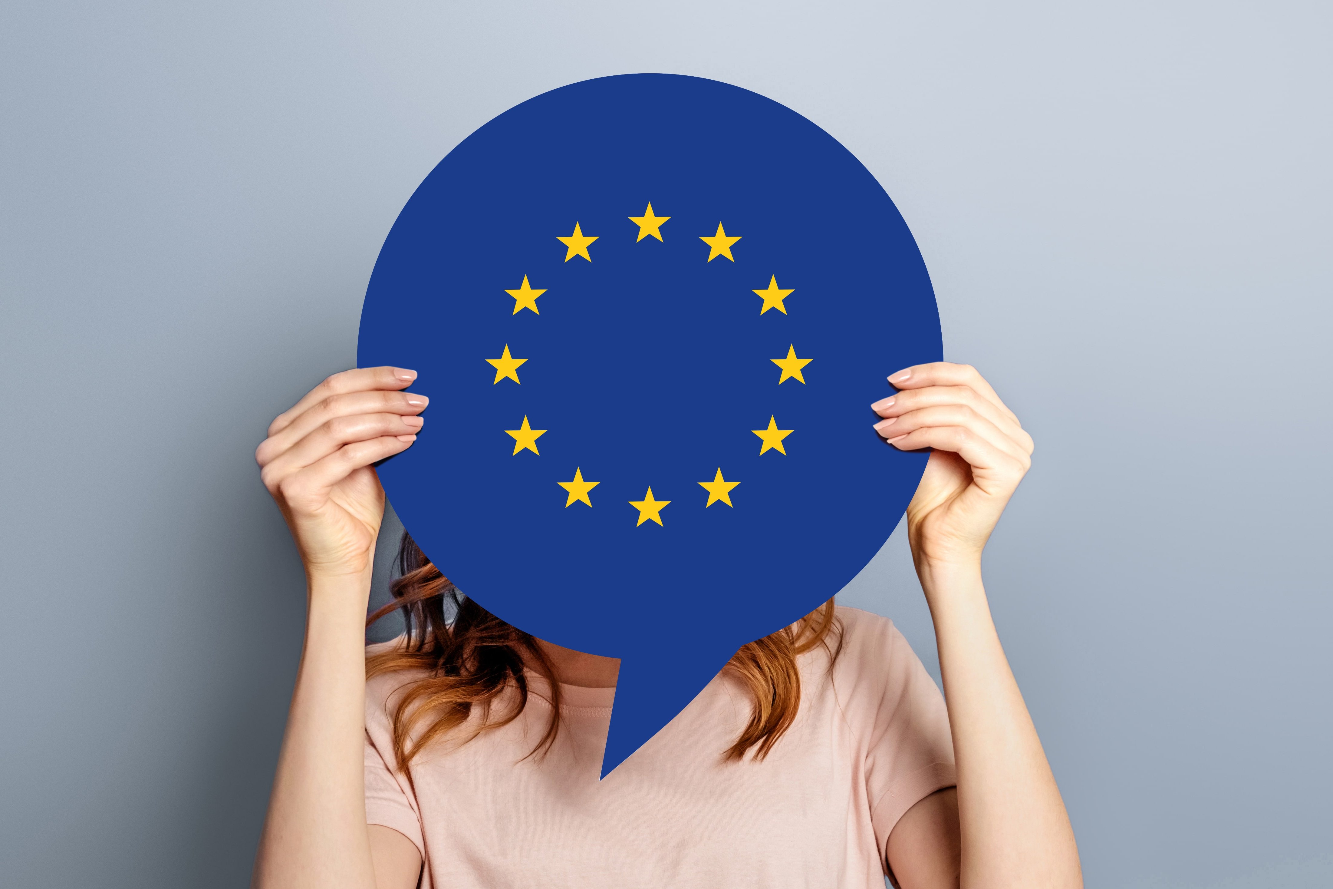 Frau hält Europaflagge vor ihrem Gesicht
