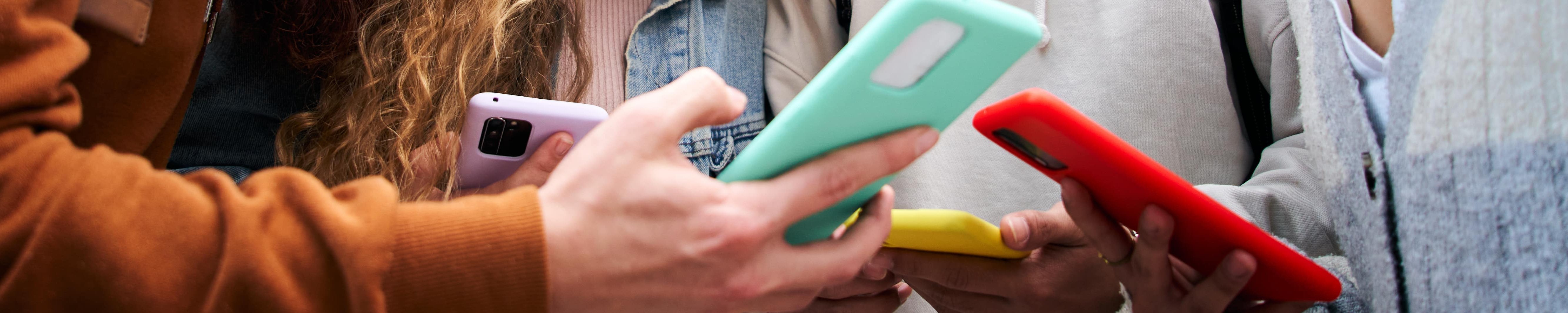 Jugendliche beugen sich über ihre Smartphones 