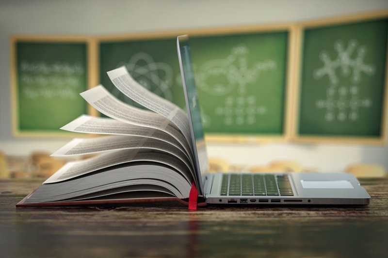 aufgeklappter Laptop im offenen Buch