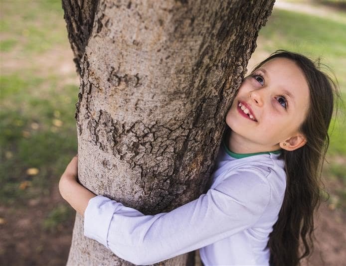Mädachen das einen Baum umarmt