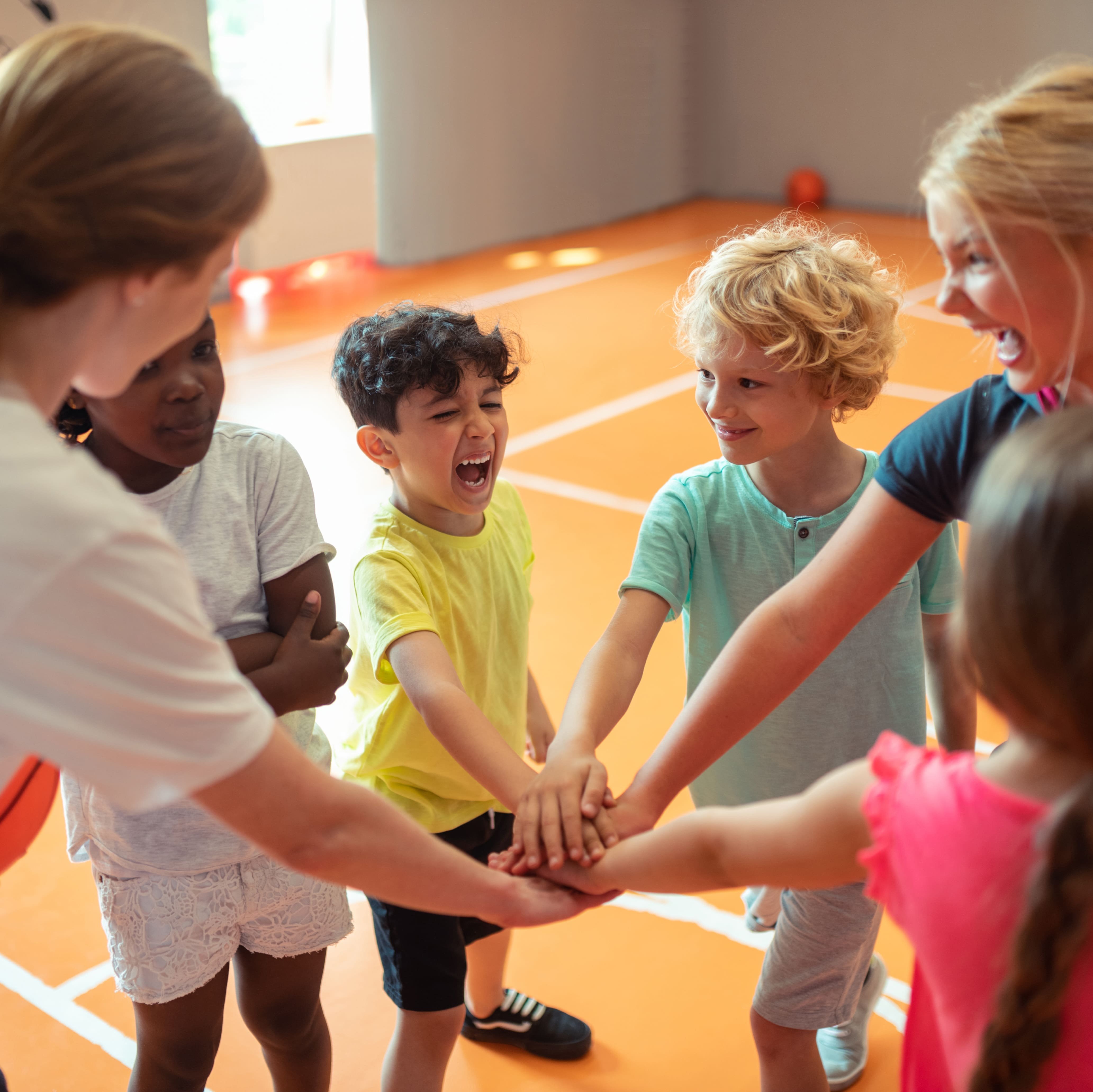 Kinder stehen im Kreis und strecken ihre Arme in die Mitte