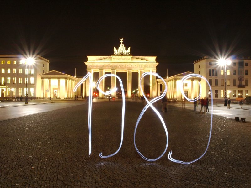 Das Brandenburger Tor bei Nacht vor dem 1989 in leuchtenden Zahlen steht. 
