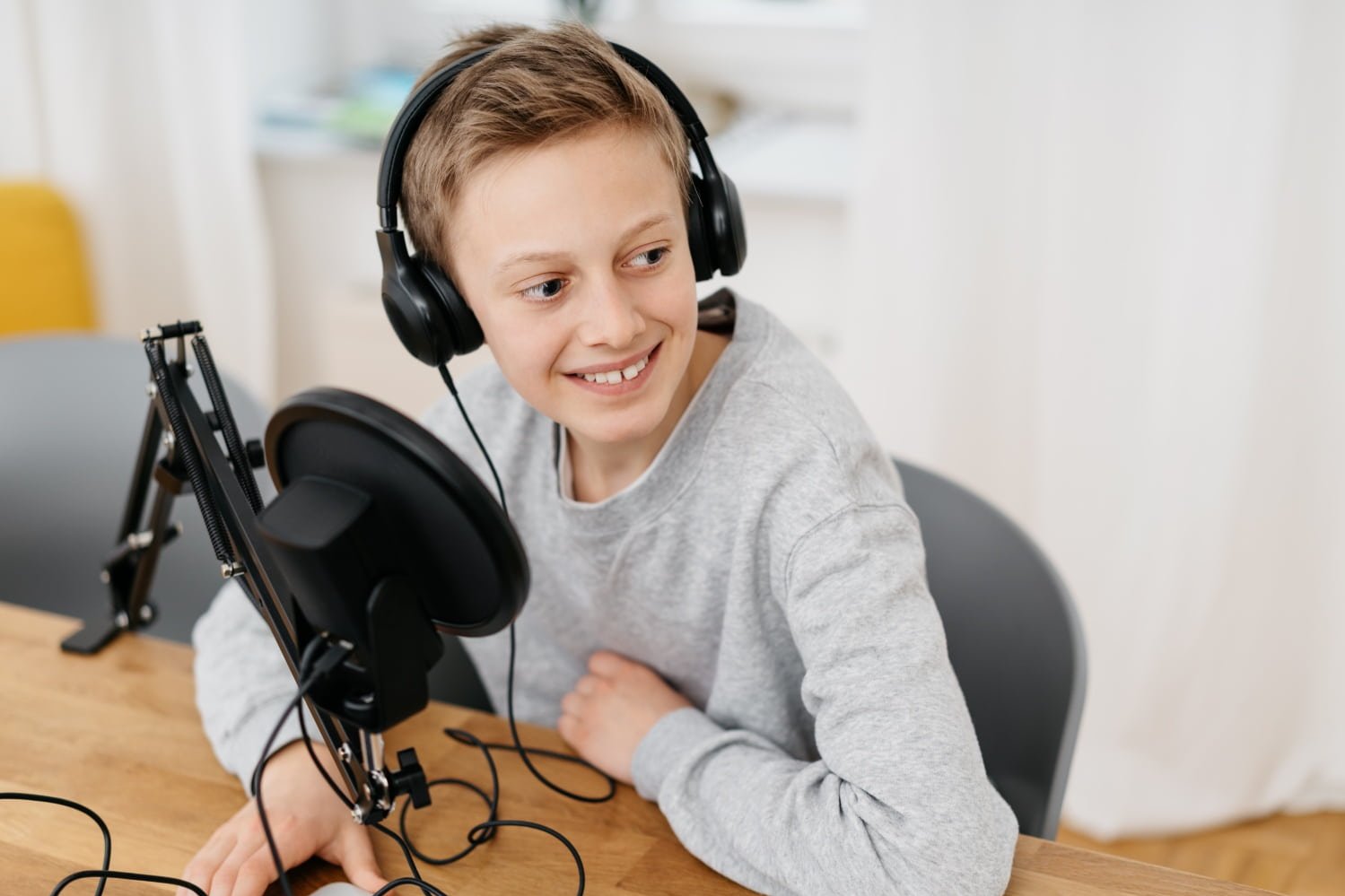 Junge mit Kopfhörer sitzt an einem Mikrofon