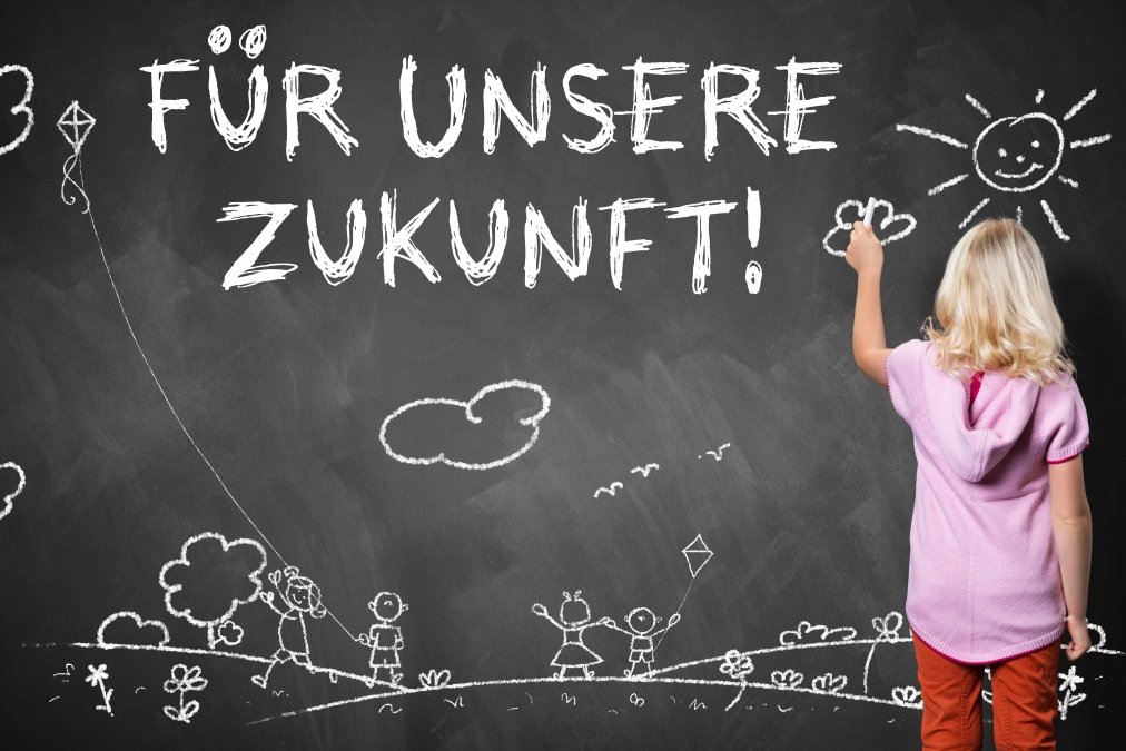 Kind schreibt mit Kreide auf eine Tafel: "Für unsere Zukunft!"