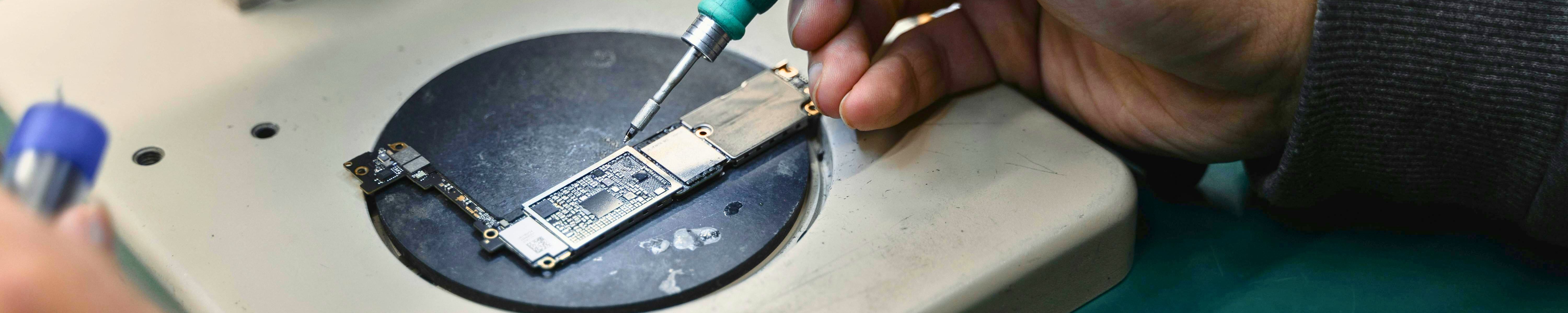 Hand die einen Mikrochip lötet. 