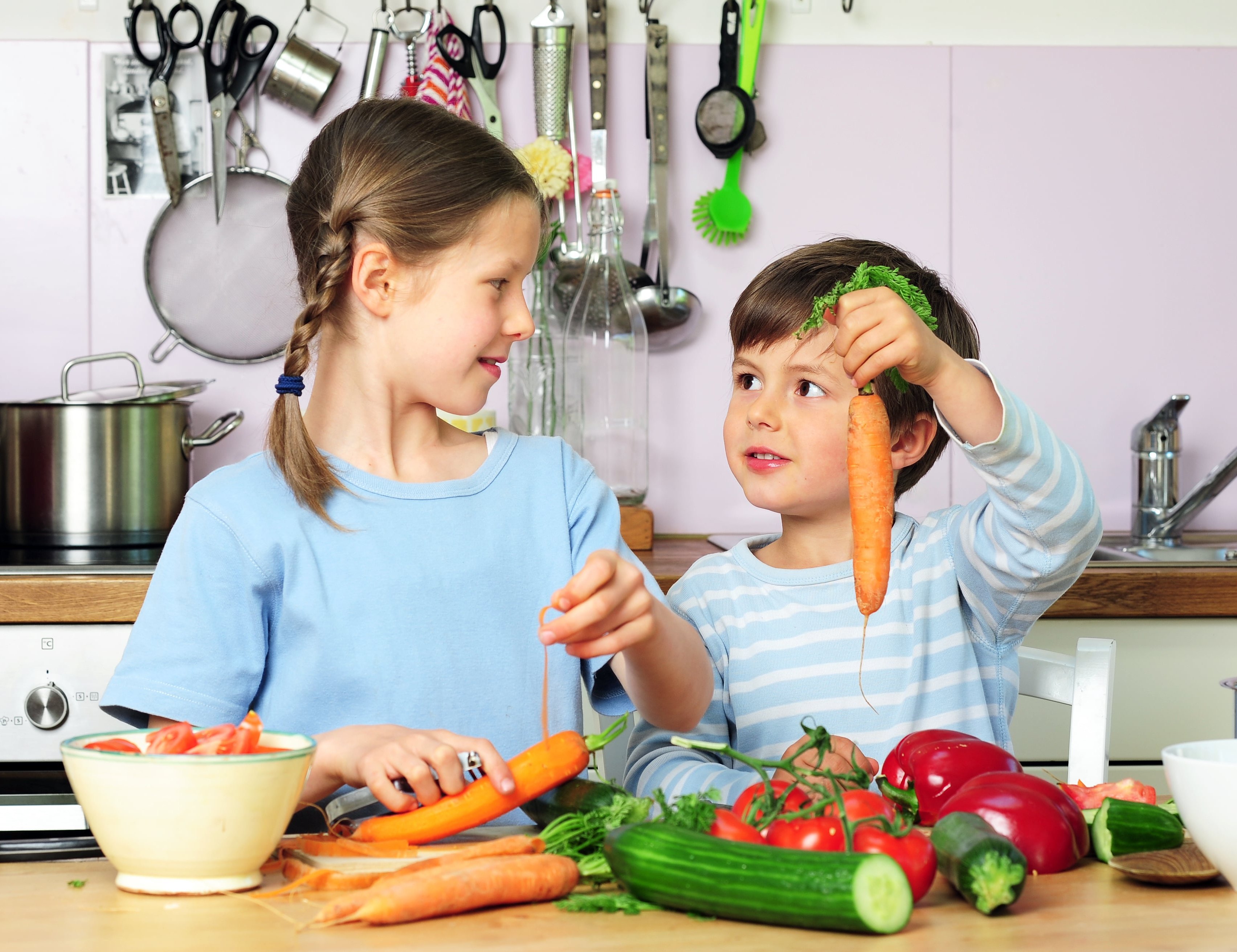 Kinder kochen gemeinsam mit Gemüse. 