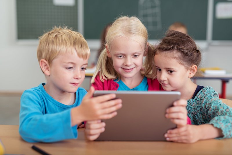 drei Kinder arbeiten gemeinsam an einem Tablet