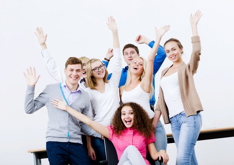 Eine Gruppe von Schülerinnen und Schüler heben freudig die Hände in die Luft. 