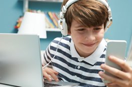 Film ab! Schulportal Jugend und Finanzen ab sofort mit Videoclips und eigenem YouTube-Kanal Junge mit Kopfhörer am Smartphone und Laptop