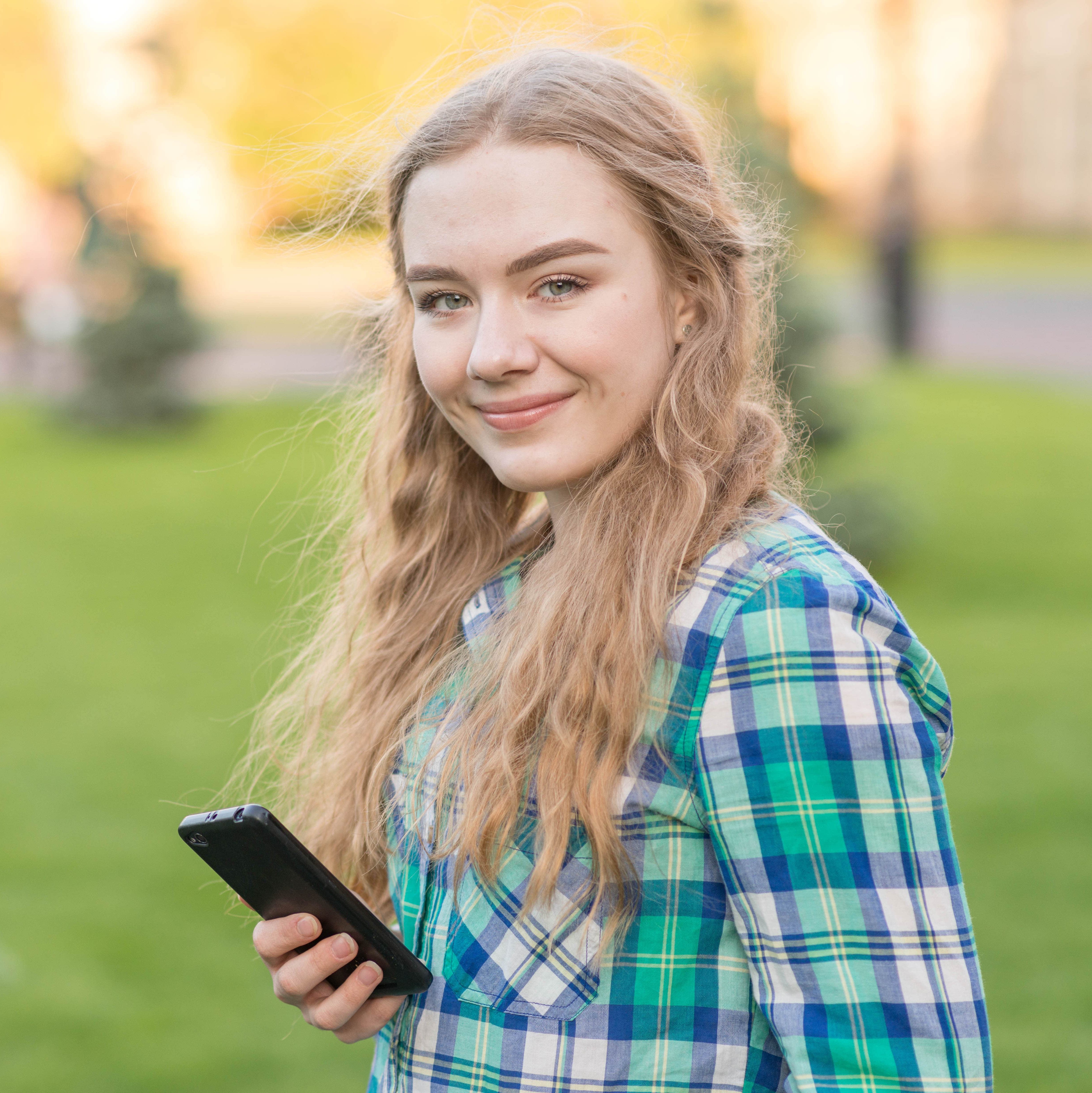 Schülerin mit Smartphone im Park
