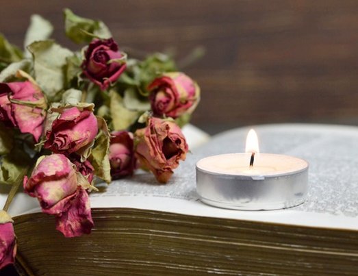verwelkte Rosen und Kerze auf einem alten Buch