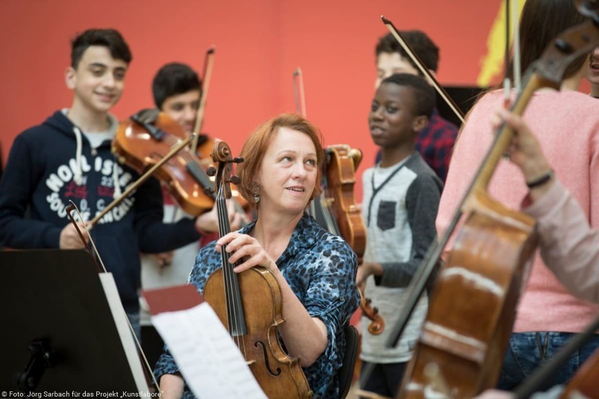 Klassenmusizieren Lehrerin und Schüler mit Streichinstrumenten