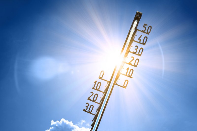 Thermometer vor dem Himmel und der Sonne.