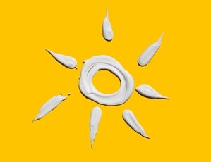 gelber Hintergrund, Sonne mit Sonnencreme gezeichnet