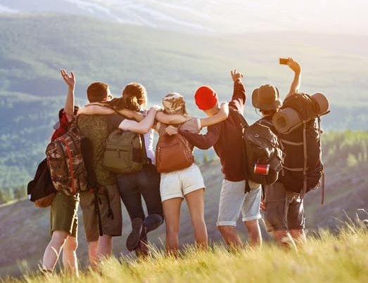 Jugendliche stehen in den Bergen und machen ein Selfie