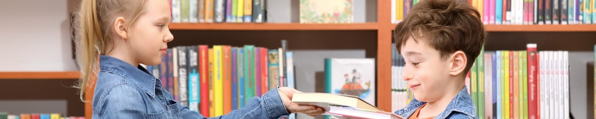 Mädchen und Junge mit Büchern in einer Bibliothek