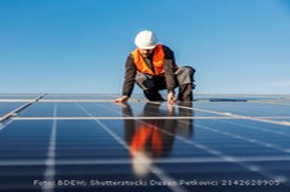 Mann arbeitet mit Schutzkleidung an einer Solaranlage (Energiewirtschaft)