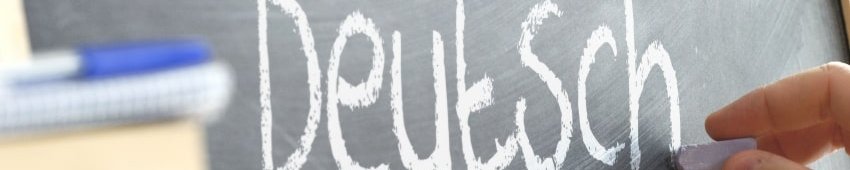 jemand schreibt auf eine Tafel das Wort "Deutsch"