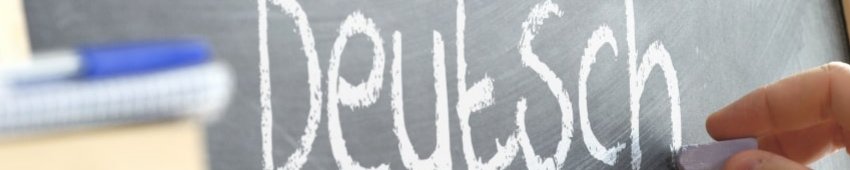 jemand schreibt auf eine Tafel das Wort "Deutsch"