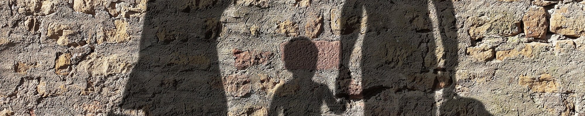 Schatten an einer Wand mit Koffern in der Hand.