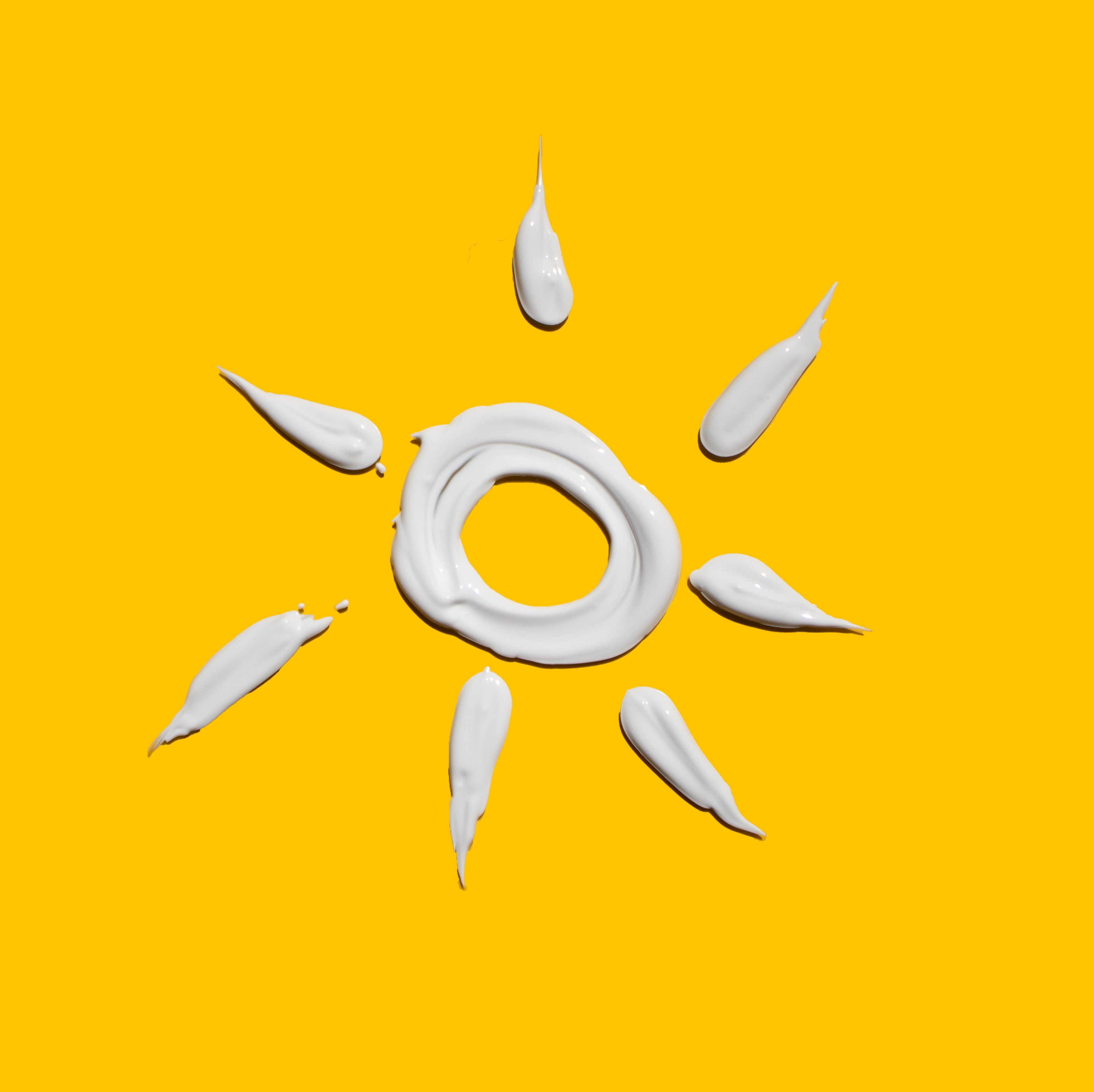 gelber Hintergrund, Sonne mit Sonnencreme gezeichnet