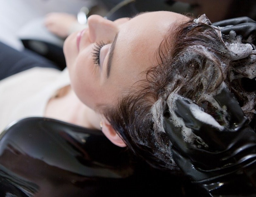 Frau bekommt beim Frisör die Haare einshampooniert