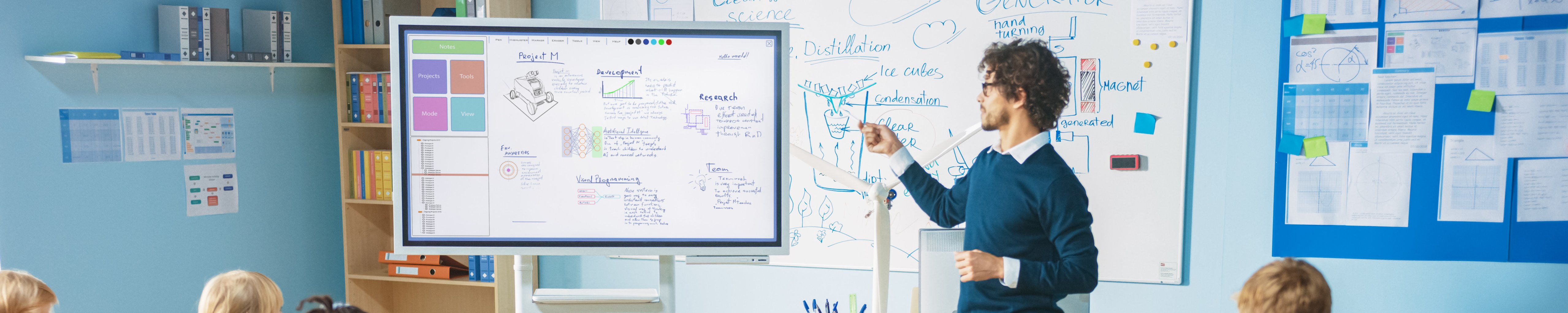 Lehrer steht an einem interaktiven Whiteboard vor der Klasse