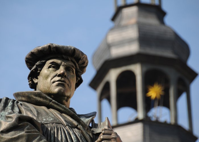 Martin Luther Lutherstatue vor einem Kirchturm