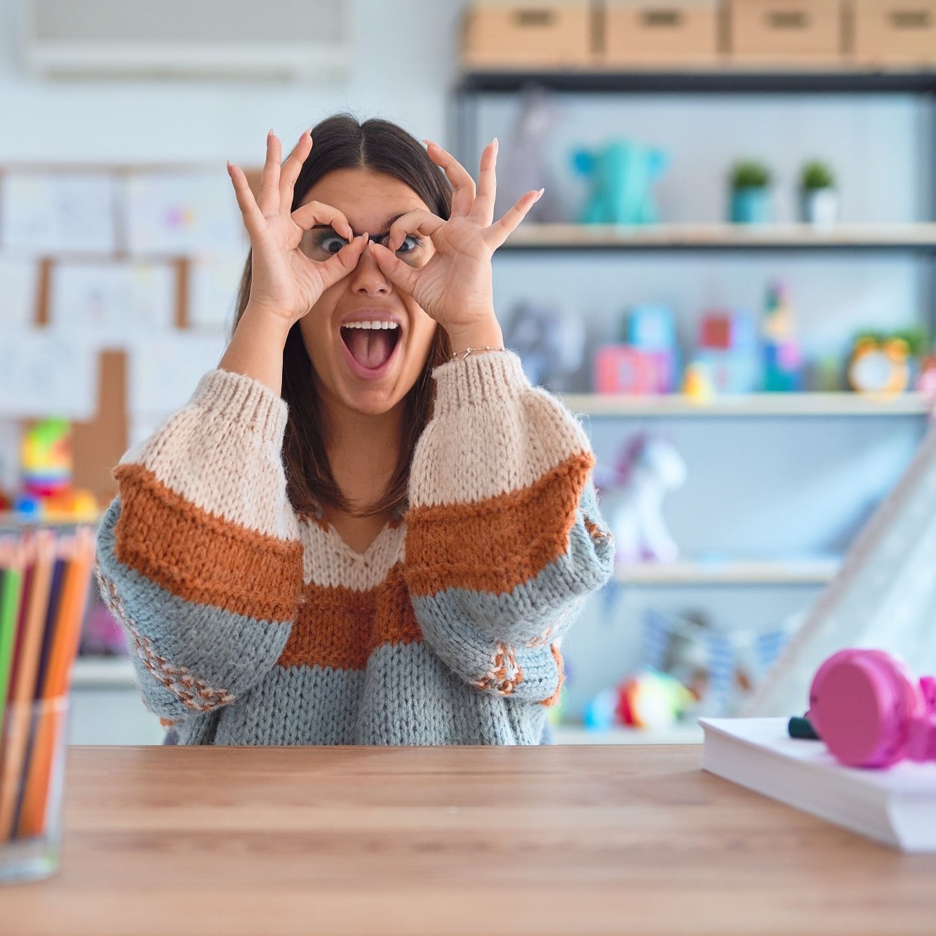 Lehrerin sitzt am Schreibtisch und schneidet Grimasse