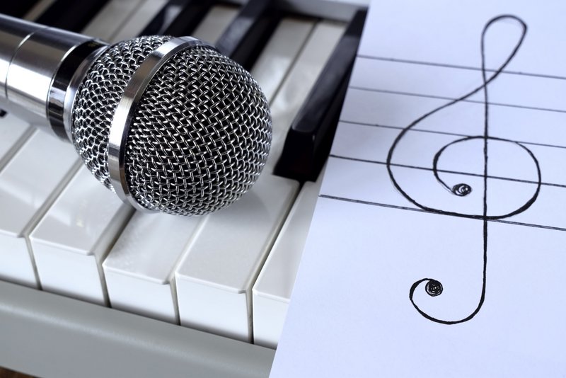 Mikrofon und Notenschlüssel auf Klavier