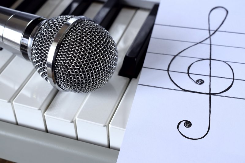 Mikrofon und Notenschlüssel auf Klavier