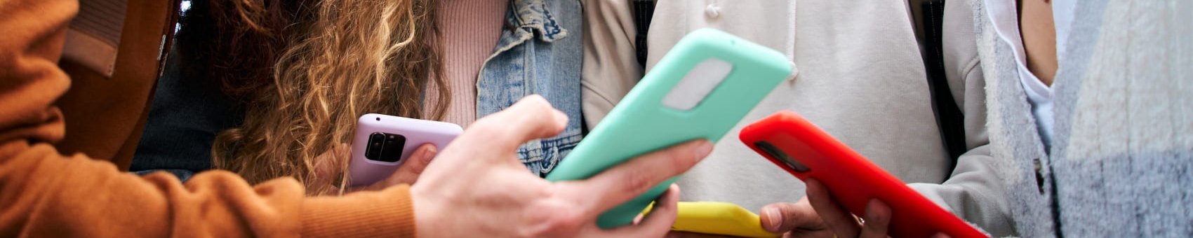 Jugendliche beugen sich über ihre Smartphones 