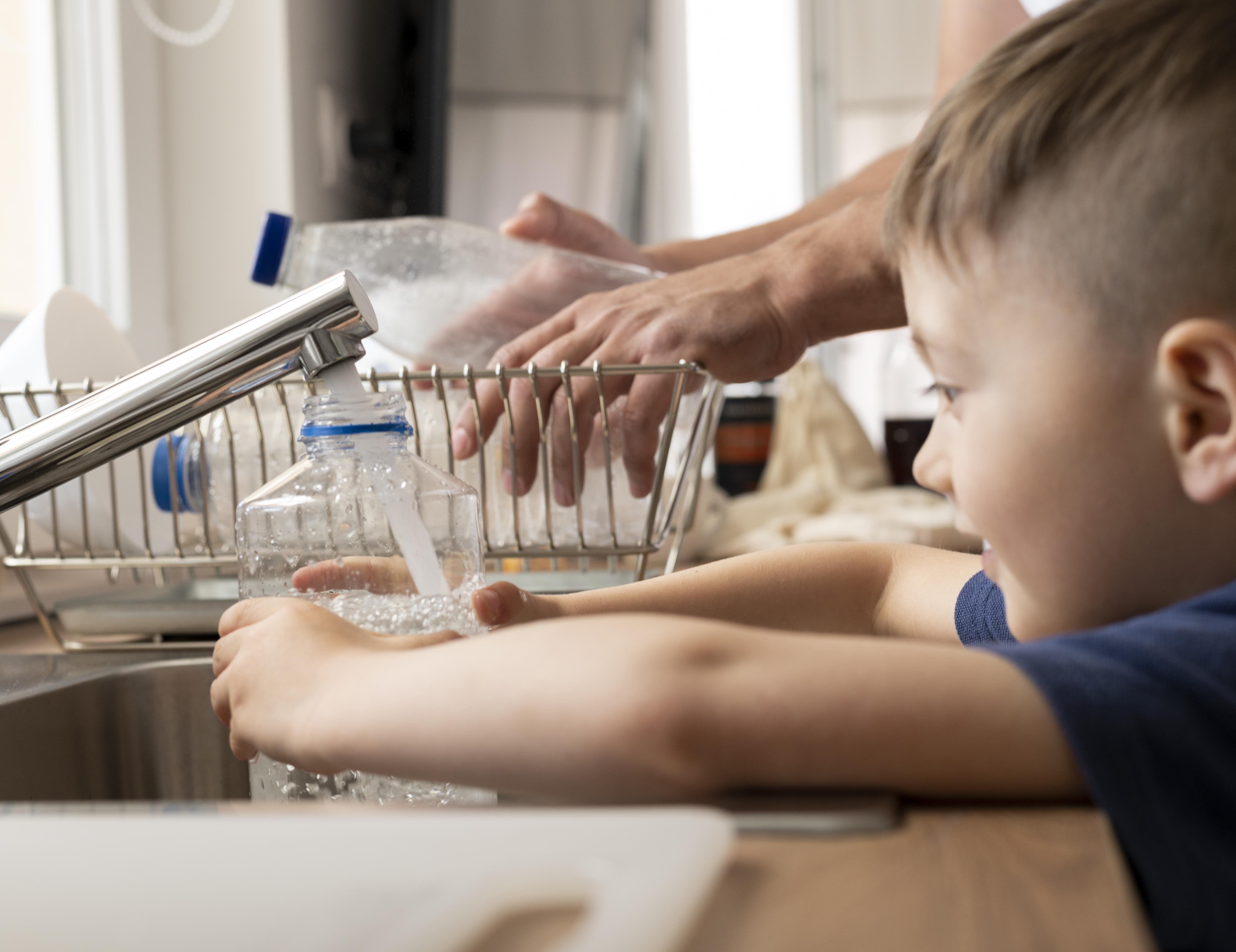 Kind befüllt eine Flasche mit Wasser
