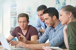 Kostenfreie Unterrichtseinheit zur Sozialen Marktwirtschaft 3 junge Männer sitzen gemeinsam an einem Laptop