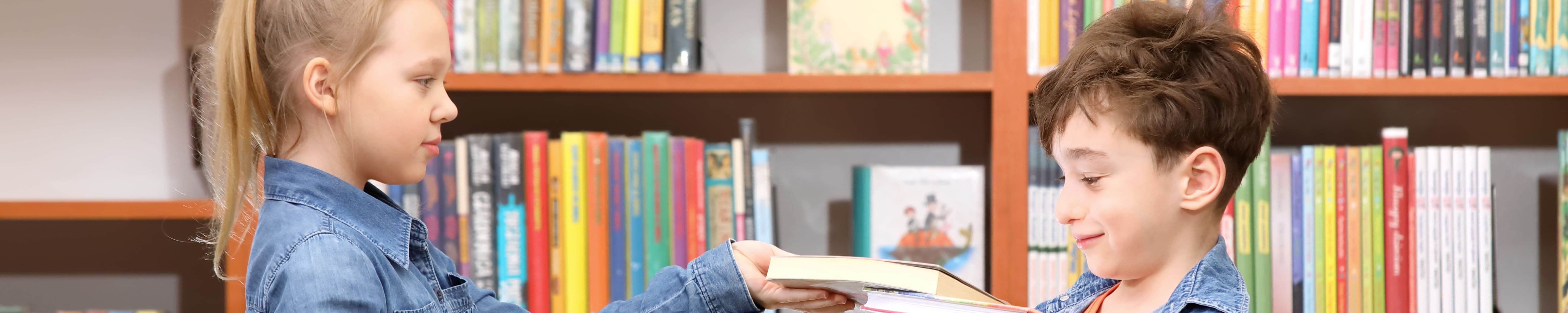 Mädchen und Junge mit Büchern in einer Bibliothek