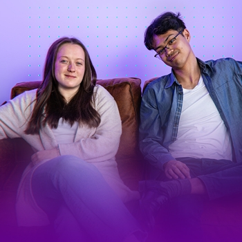 Zwei junge Erwachsene sitzen auf einem Sofa; links junge Frau mit braunen Haaren; rechts junger Mann mit Brille