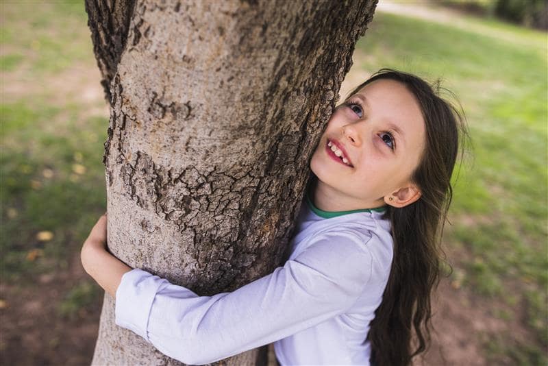 Mädachen das einen Baum umarmt