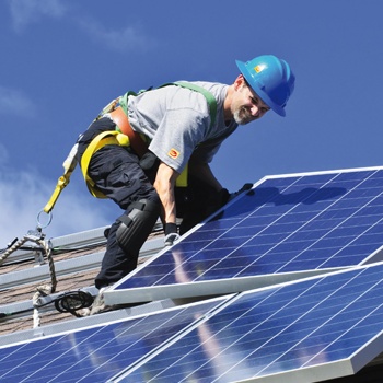 Handwerker mit Solarplatten auf dem Dach
