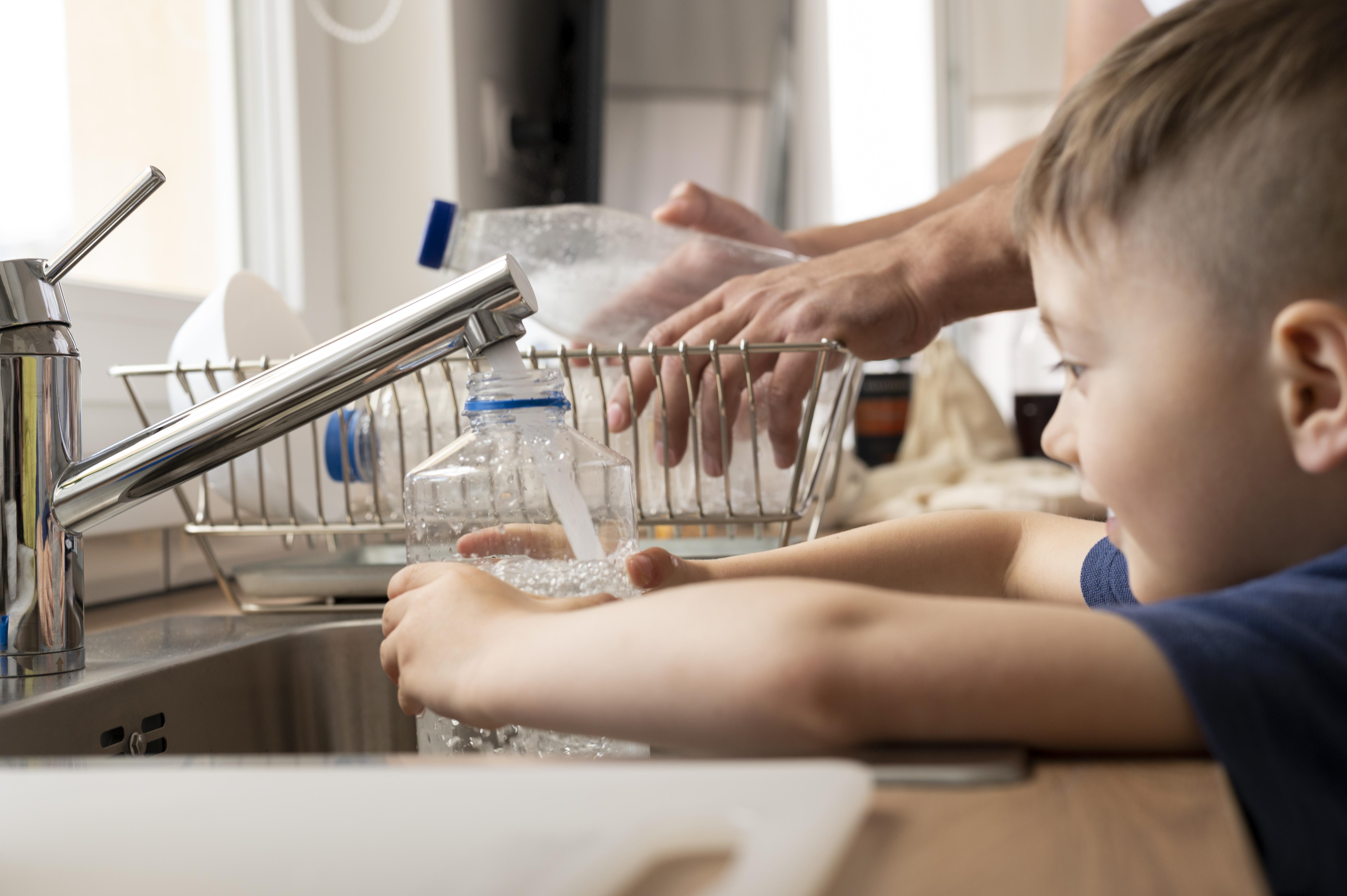Kind befüllt eine Flasche mit Wasser