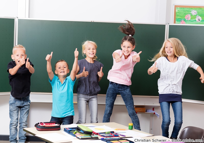 Kinder springen vor einer Tafel