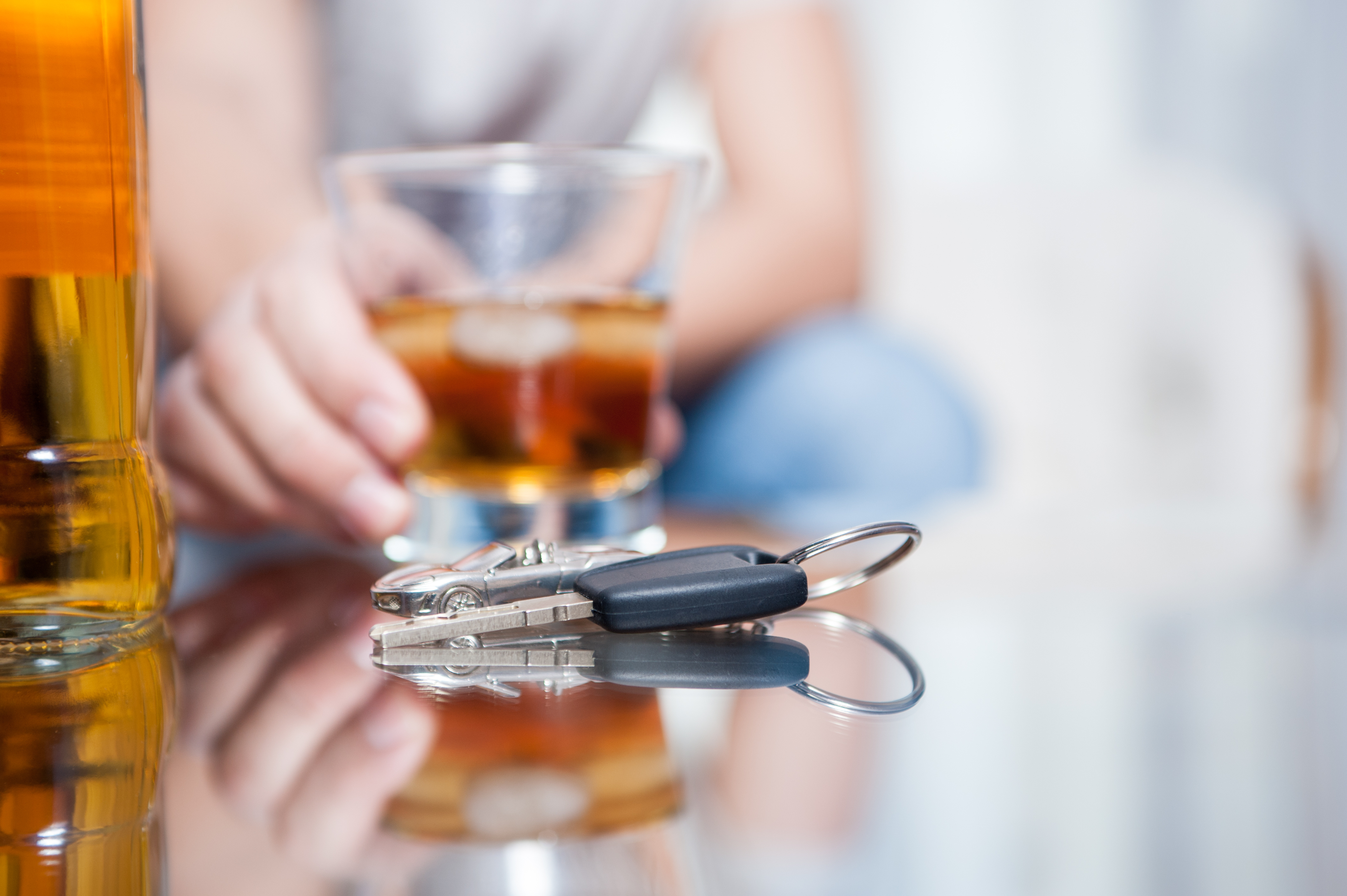 Autoschlüssel und Schnapsglas auf Glastisch