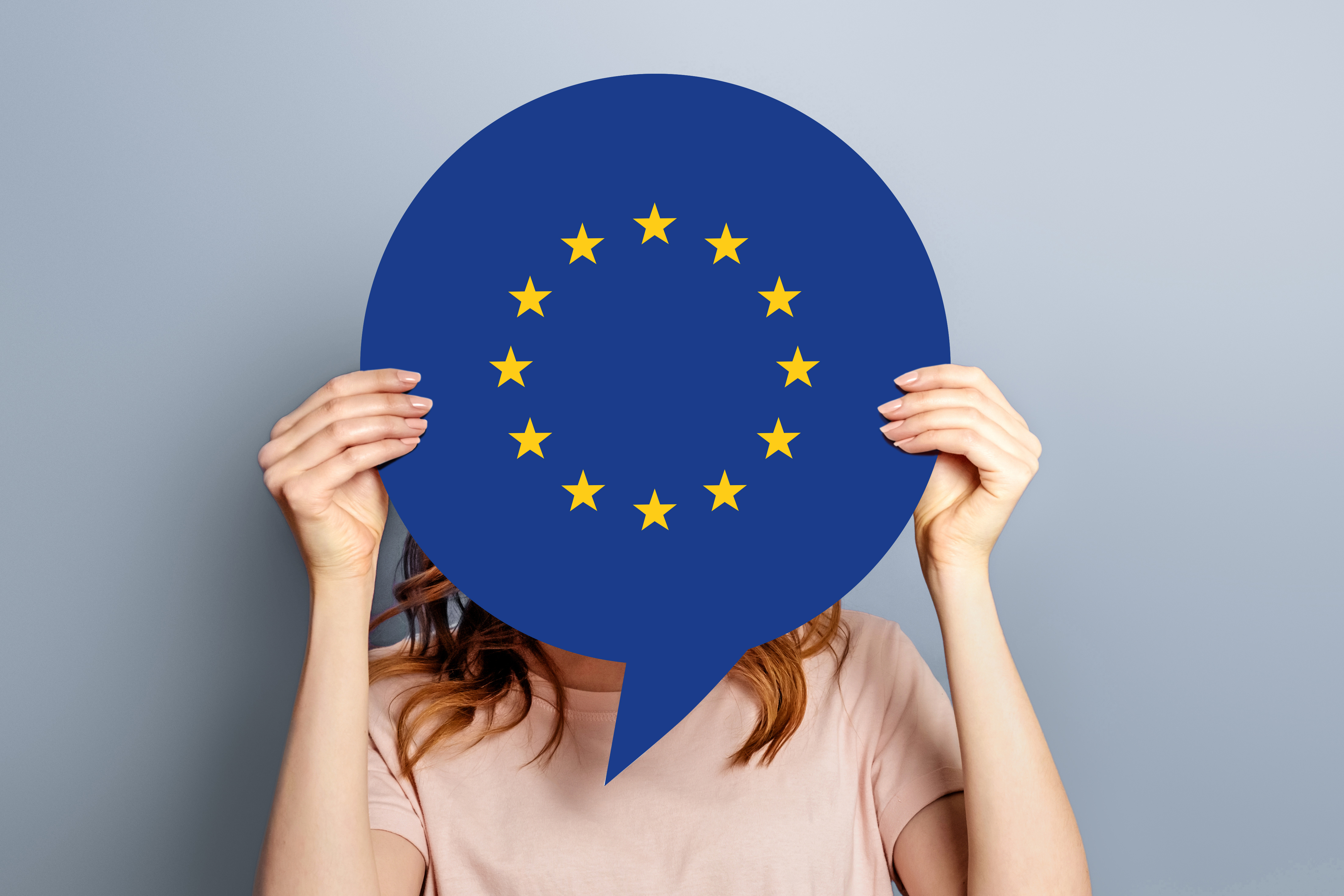 Frau hält Europaflagge vor ihrem Gesicht