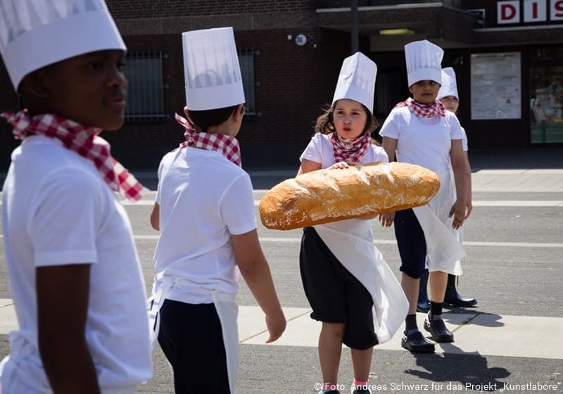 Kinder mit Broten und Kochmützen