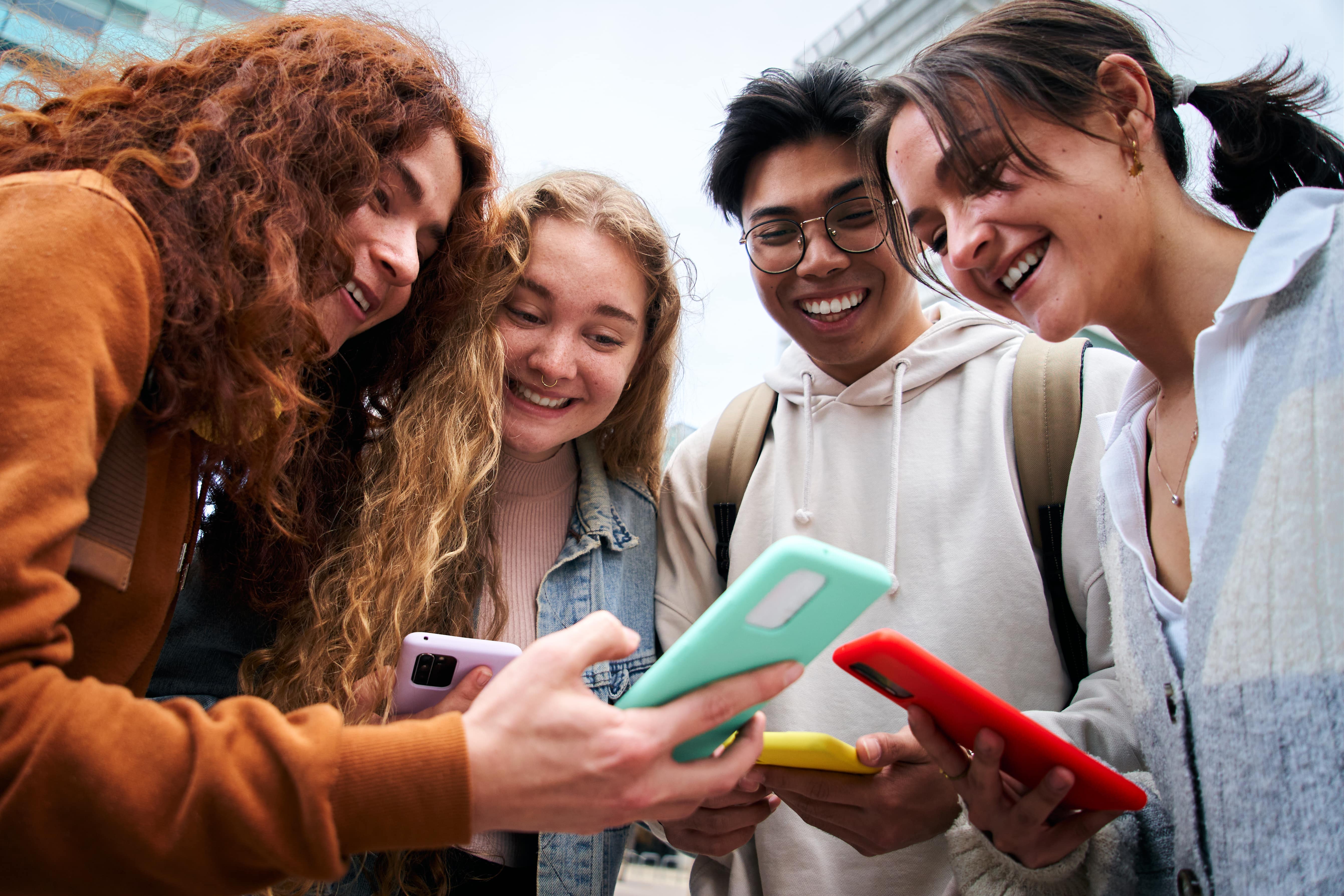 Schüler und Schülerinnen beugen sich über ihre Smartphones